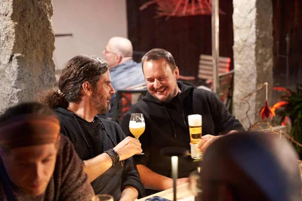 zwei Gäste lächelnd posten sich mit Bier zu